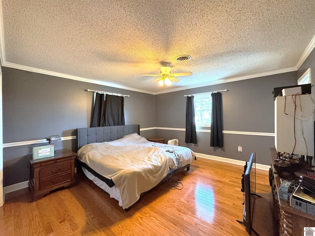 bedroom with visible vents, a ceiling fan, a textured ceiling, light wood-style floors, and crown molding