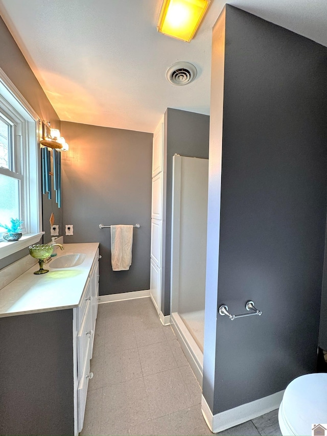 bathroom with visible vents, a shower stall, vanity, and baseboards