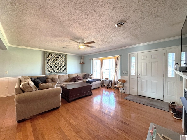 living area featuring visible vents, crown molding, a ceiling fan, and wood finished floors