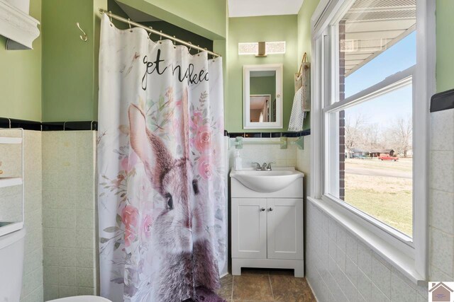 full bath featuring tile walls and vanity