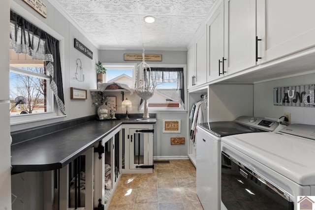 clothes washing area featuring baseboards, cabinet space, separate washer and dryer, an ornate ceiling, and crown molding