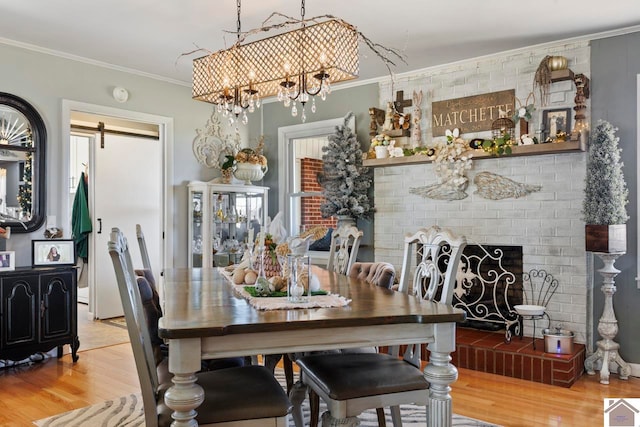 dining area with crown molding, a chandelier, a barn door, a fireplace, and wood finished floors