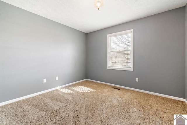 carpeted spare room with visible vents and baseboards