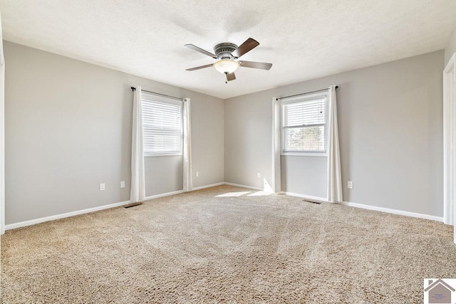 carpeted empty room featuring a textured ceiling, visible vents, baseboards, and ceiling fan