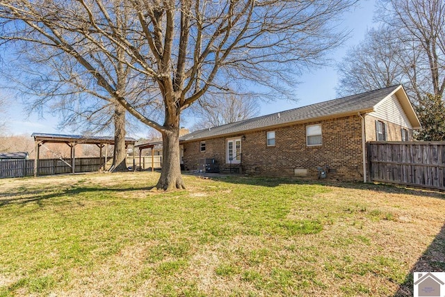 back of house featuring brick siding, crawl space, a lawn, and a fenced backyard