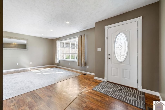 foyer with hardwood / wood-style flooring, visible vents, and baseboards