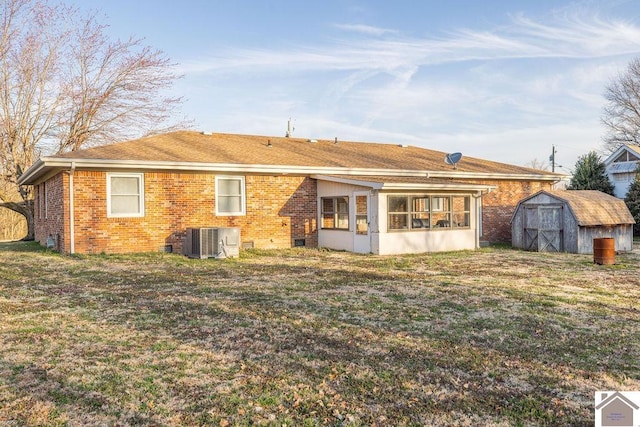 rear view of property featuring central air condition unit, brick siding, a lawn, and a shed