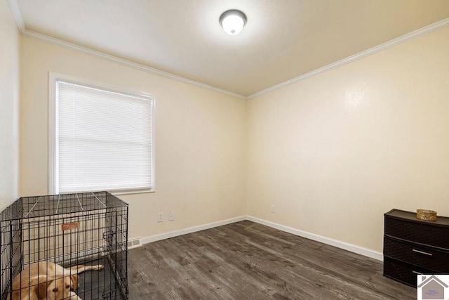 empty room with visible vents, baseboards, wood finished floors, and ornamental molding