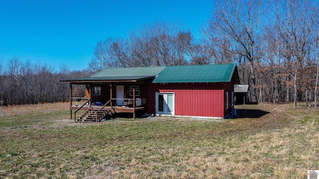 view of front of home with a front lawn, a wooded view, and metal roof