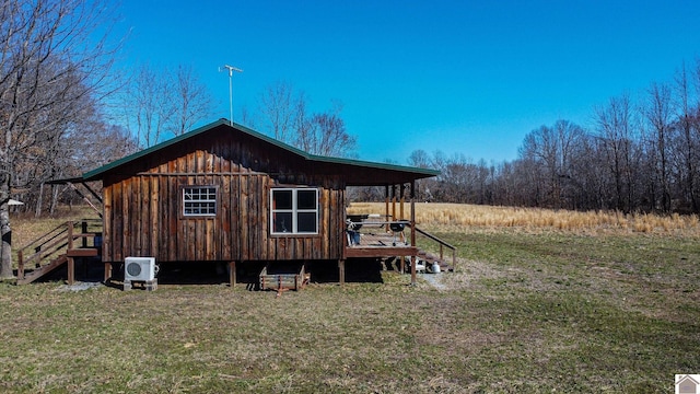 exterior space with ac unit, a yard, and board and batten siding