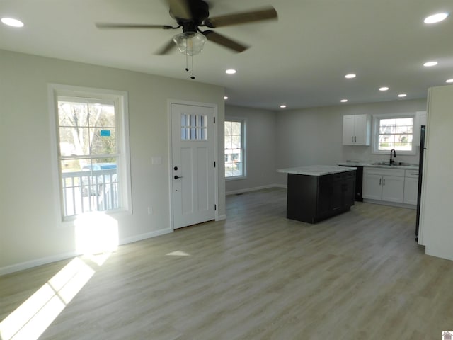 kitchen with recessed lighting, a kitchen island, light wood-type flooring, and a sink