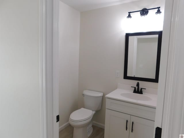 bathroom featuring vanity, toilet, wood finished floors, and baseboards