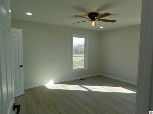 spare room featuring wood finished floors, a ceiling fan, baseboards, and visible vents