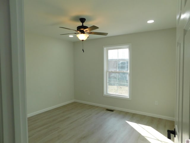 unfurnished room with visible vents, light wood-style flooring, a ceiling fan, and baseboards