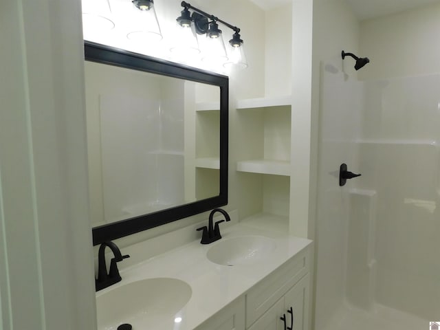 bathroom featuring double vanity, a shower, and a sink