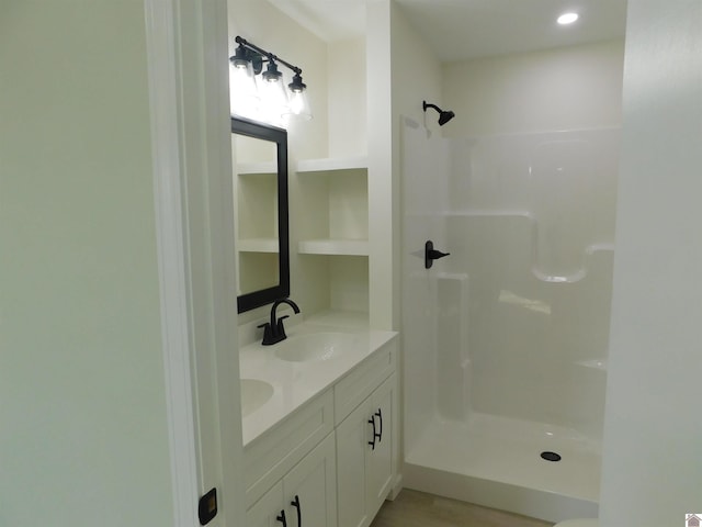 bathroom with a sink, walk in shower, and double vanity