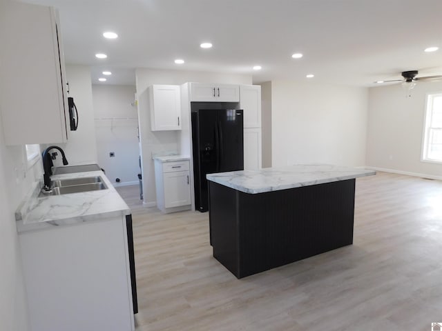 kitchen featuring ceiling fan, a sink, white cabinets, black fridge with ice dispenser, and light wood-style floors