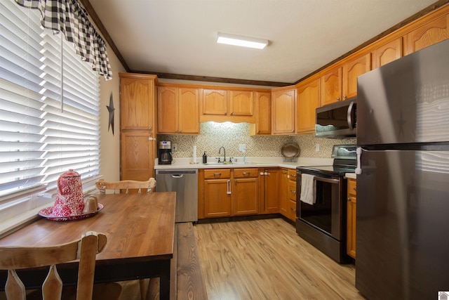 kitchen featuring light wood-type flooring, a sink, backsplash, stainless steel appliances, and light countertops