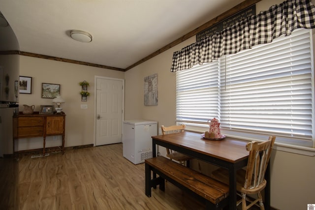 dining room with light wood-style flooring, baseboards, and ornamental molding