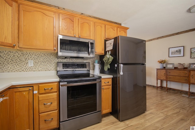 kitchen with light countertops, tasteful backsplash, light wood-type flooring, and appliances with stainless steel finishes