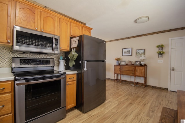 kitchen featuring light countertops, backsplash, light wood finished floors, and stainless steel appliances