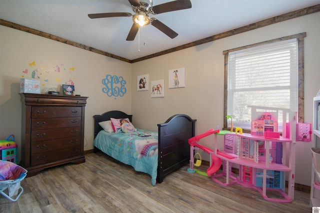 bedroom with crown molding, wood finished floors, and ceiling fan