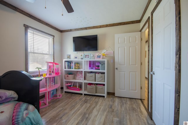 bedroom featuring ornamental molding, a ceiling fan, and wood finished floors