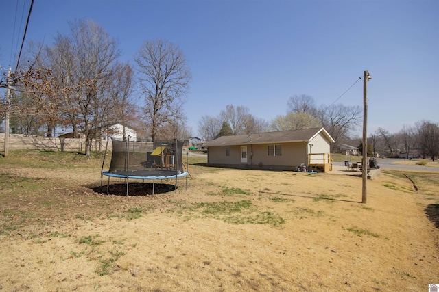 view of yard with a trampoline and fence