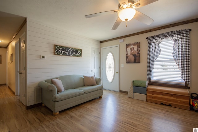 living room with visible vents, light wood-style floors, and ceiling fan