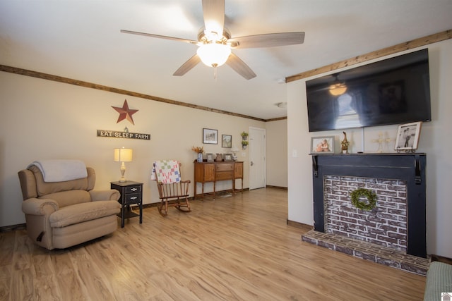 sitting room with a ceiling fan, crown molding, wood finished floors, and baseboards