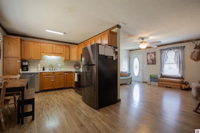 kitchen with light wood-type flooring, a ceiling fan, a sink, appliances with stainless steel finishes, and light countertops