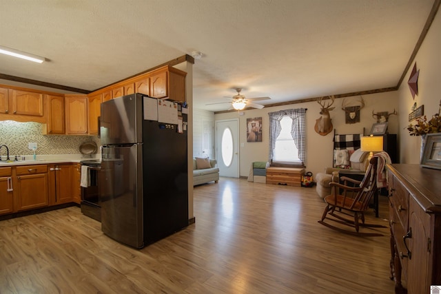 kitchen featuring black range with electric stovetop, light wood-style flooring, a ceiling fan, open floor plan, and freestanding refrigerator