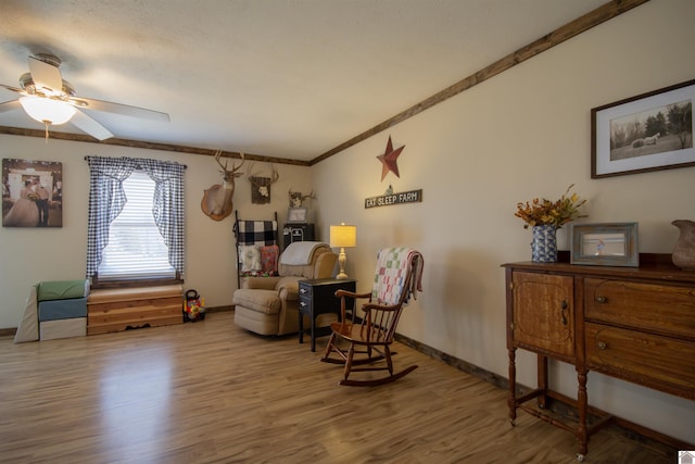 sitting room featuring a ceiling fan, wood finished floors, baseboards, and ornamental molding