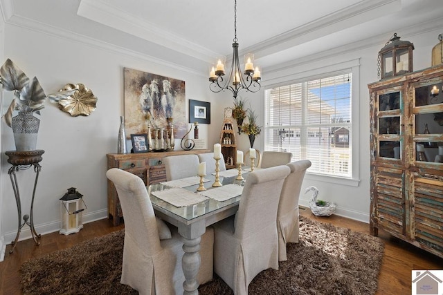 dining space featuring ornamental molding, a tray ceiling, wood finished floors, baseboards, and a chandelier