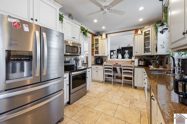 kitchen with tasteful backsplash, glass insert cabinets, appliances with stainless steel finishes, a ceiling fan, and a sink