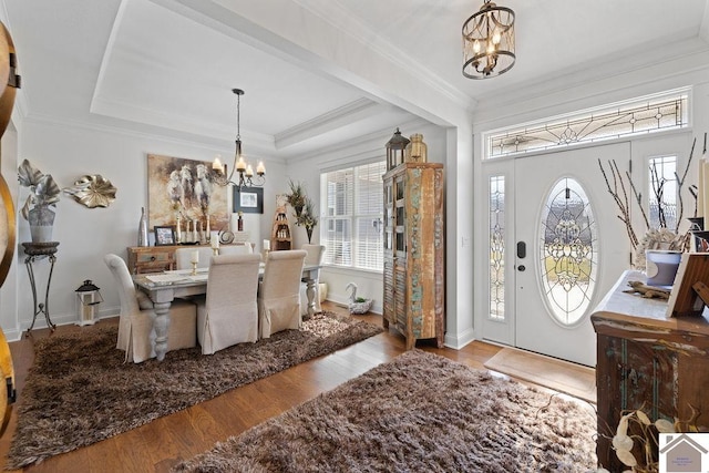 entryway with an inviting chandelier, plenty of natural light, wood finished floors, and a tray ceiling