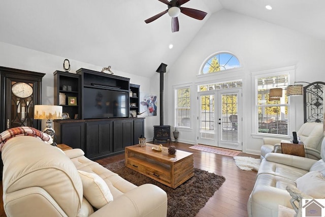 living area featuring high vaulted ceiling, hardwood / wood-style flooring, recessed lighting, ceiling fan, and a wood stove