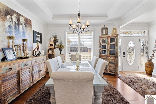 dining area with an inviting chandelier, wood finished floors, and a tray ceiling