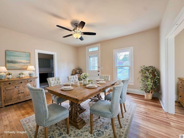 dining area featuring light wood-type flooring, baseboards, and a ceiling fan