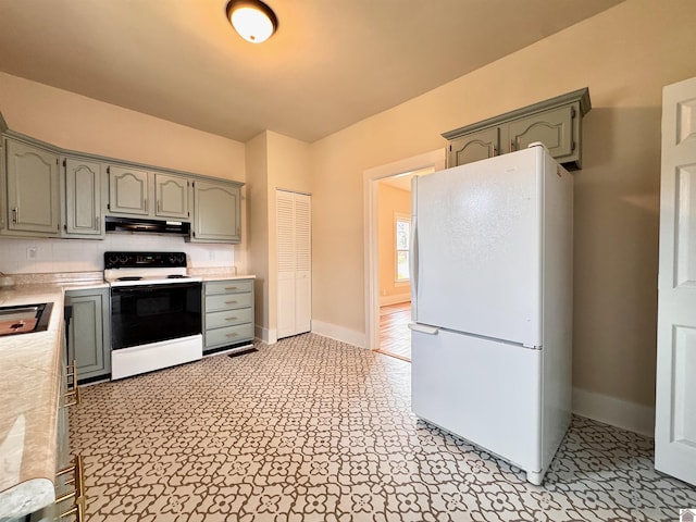 kitchen featuring baseboards, freestanding refrigerator, electric range oven, light countertops, and under cabinet range hood