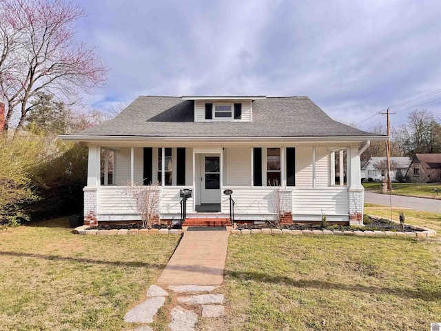 bungalow with covered porch, a shingled roof, and a front yard