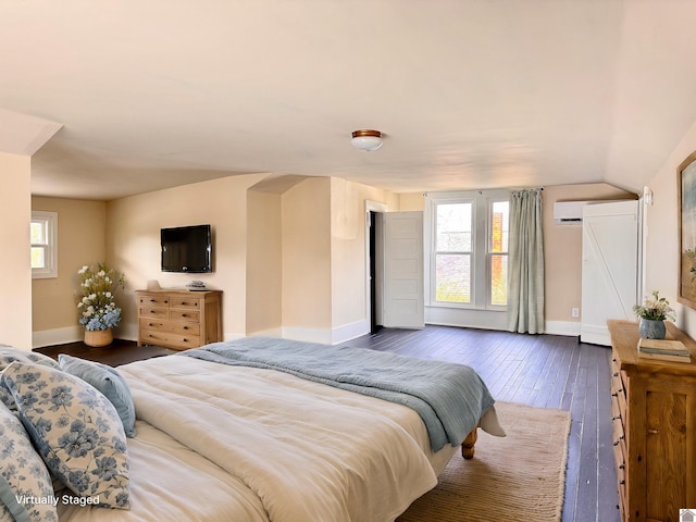 bedroom with dark wood finished floors, an AC wall unit, baseboards, and vaulted ceiling