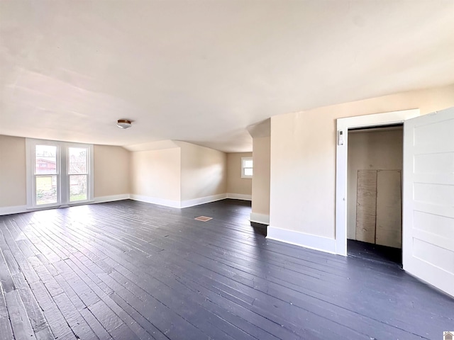 unfurnished room with baseboards and dark wood-style flooring