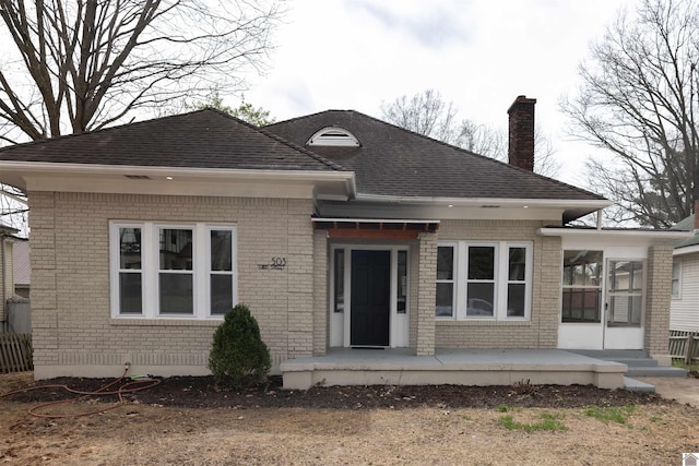 503 3rd St, Fulton, KY 42041 - view of front of property with brick siding, a chimney, a sunroom, and a shingled roof
