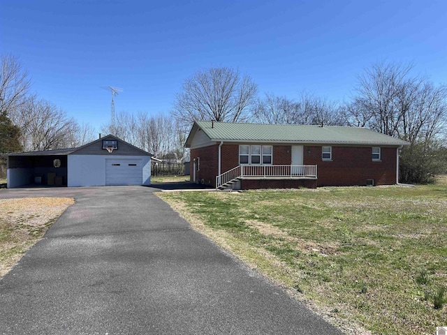 ranch-style home with aphalt driveway, a garage, brick siding, an outbuilding, and a porch