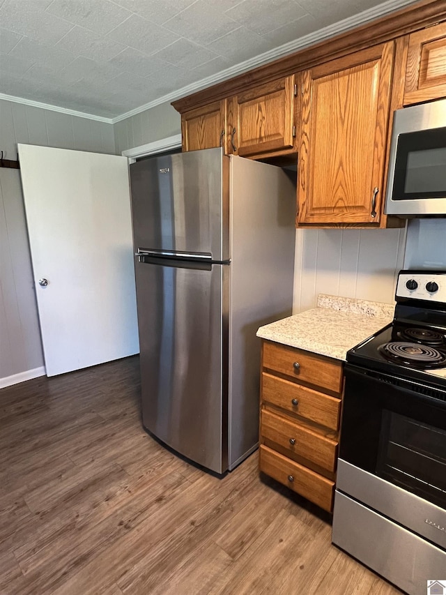 kitchen featuring light wood-type flooring, stainless steel appliances, crown molding, and brown cabinets