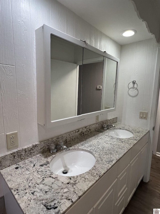 full bath featuring double vanity, a sink, and wood finished floors