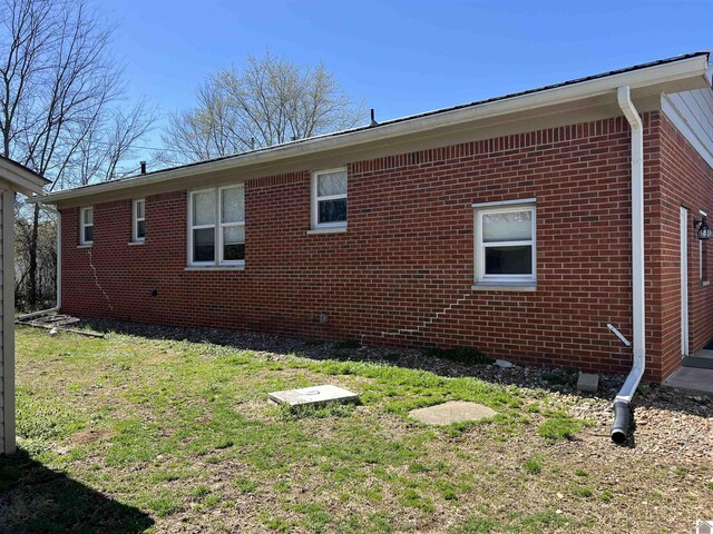 view of side of property with a lawn and brick siding