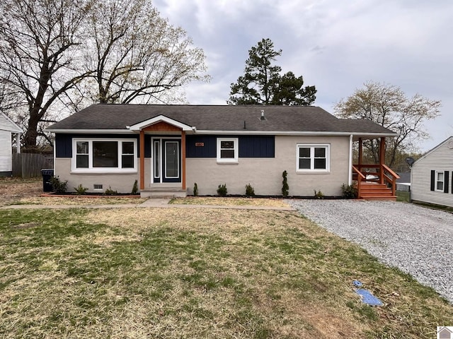 view of front facade with fence, stucco siding, roof with shingles, and a front lawn