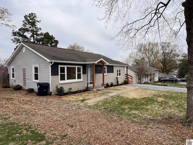 ranch-style home with gravel driveway and roof with shingles